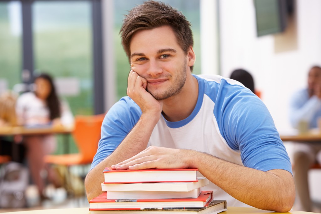 Male Student Studying In Classroom With Books